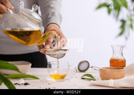 Versata da una teiera tazza di tè su un tavolo di legno Foto Stock