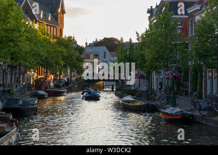 Leiden, Olanda - Giugno 26, 2019: Case, barche e biciclette a Oude Rijn canal al tramonto Foto Stock