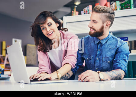 Felice designer che lavorano insieme su laptop Foto Stock