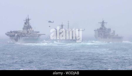 190714-N-MT581-0005 Mar Arabico (Luglio 14, 2019) Amphibious Assault nave USS Boxer (LHD 4), a sinistra e a amphibious dock landing ship USS harpers Ferry (LSD 49), estrema destra, condurre a una ricostituzione in mare evolution con fast combattere la nave appoggio USNS Arctic (T-AOE 8). Boxer e harpers Ferry sono parte del Boxer anfibio gruppo pronto e la XI Marine Expeditionary Unit team e sono dispiegati per la Quinta Flotta area di operazione a sostegno di operazioni navali per garantire stabilità marittimo e la sicurezza nella regione centrale di collegamento del Mediterraneo e del Pacifico attraverso il Western Ocea indiano Foto Stock