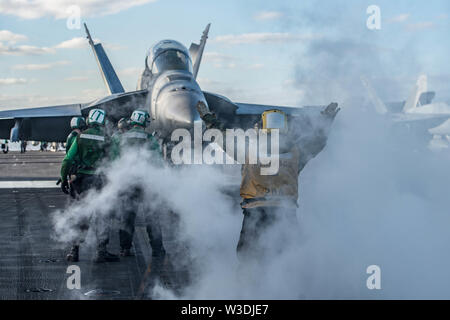 190714-N-CL027-1239 CORAL SEA (Luglio 14, 2019) di aviazione di Boatswain Mate (movimentazione) terza classe Ashley pieghe, da Brooklyn, New York, dirige un'F/A-18F Super Hornet da Strike Fighter Squadron (VFA) 102 in posizione di lancio sul ponte di volo a bordo della marina distribuita portaerei USS Ronald Reagan (CVN 76). Ronald Reagan è che partecipano a Talisman Sabre 2019, che illustra la vicinanza dell'Australia e Stati Uniti alliance e la resistenza delle strutture militari del rapporto. È l'ottava iterazione di questo esercizio. Ronald Reagan, il portabandiera del Carrier Strike Grou Foto Stock