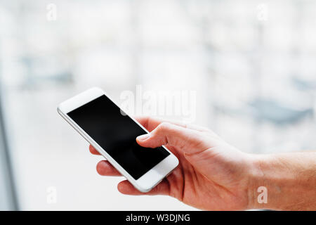 La mano di un uomo con uno smartphone e toccando lo schermo Foto Stock