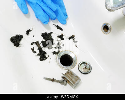 Lavandino intasato con massa di capelli e sporcizia in bagno. Foto Stock