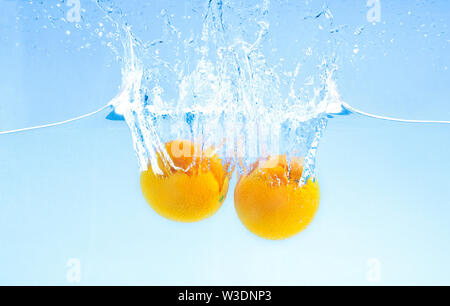 Due arance mature caduta profondamente sotto l'acqua con grande splash Foto Stock