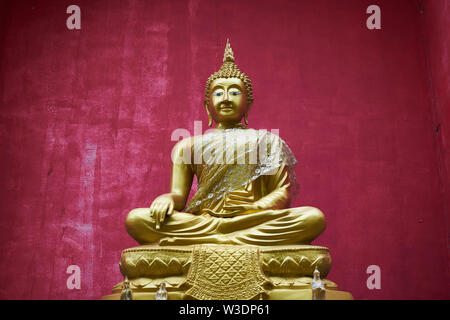 Budda seduto in ricco rosso alcova al Wat Buppharam in Chiang Mai, Thailandia. Foto Stock