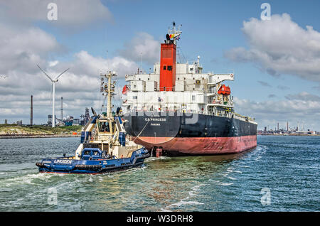 IJmuiden, Paesi Bassi, luglio 14, 2019: grande nave da carico con rimorchiatore, entrando in mare del Nord canal legato ad Amsterdam, con le acciaierie in backgr Foto Stock