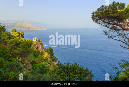 Isola di Capri. Magnifica vista dal mare sulle sponde rocciose dell'isola di Capri e le montagne che circondano la Costiera Amalfitana. Foto Stock