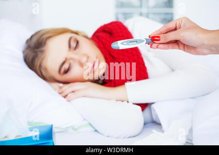 Febbre e freddo. Ritratto di donna bella catturati influenza, avendo mal di testa e ad alta temperatura. Primo piano della ragazza malata coperti in coperta, sensazione di malessere Foto Stock