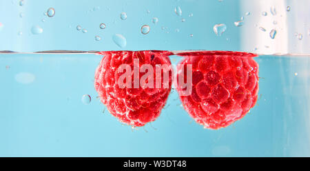 Bella lampone in acqua con bolle. Organici di cibo sano. Bacche di dolci. Estate raccolto. Lamponi maturi isolati. Bacche di colore rosso sfondo. Cle Foto Stock