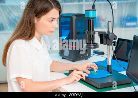 Lavoratore di sesso femminile nel controllo di resina LCD / DLP / SLA stampante 3D nel laboratorio di tecnologia Foto Stock