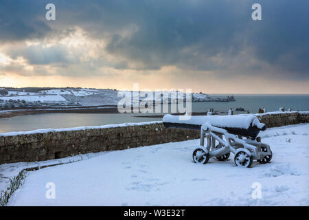 Cannon nel Duca di Leeds batteria (aka il giardino batteria), Garrison, Hugh Town, Isole Scilly, UK, guardando sopra Porth Cressa, durante una tempesta di neve Foto Stock