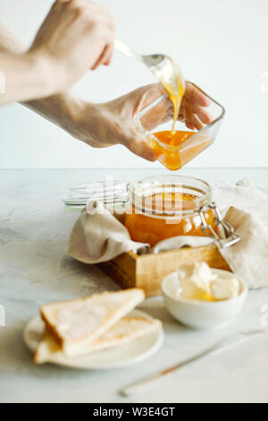 Una pila di deliziosi toast con burro per la prima colazione la mattina tabella, mano versa il miele sulla parte superiore.colazione salutare concetto alimentare.Un elegante prima colazione Foto Stock