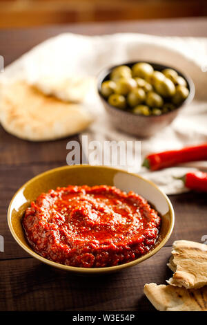 Una sana piccante, cremosa antipasto vegetariano o uno spuntino con arrosti di pepe rosso dip con harissa, pita e olive che è rapido e facile da preparare Foto Stock