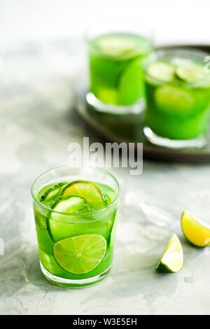 In casa ghiacciata alla moda di tè verde Matcha o limonata con il cetriolo e lime in un bicchiere su sfondo grigio chiaro. Freddo salutare vegan bevanda Foto Stock