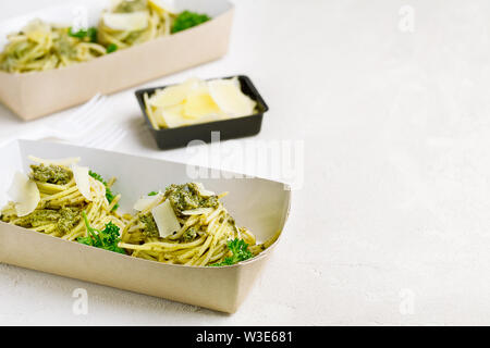 Pasta al pesto decorate con parmigiano in un tradizionale take-away box dal ristorante su sfondo bianco. Ristorante Consegna del cibo Foto Stock