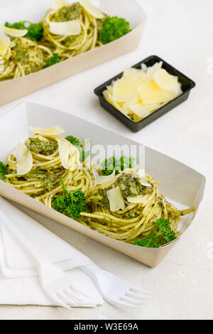 Pasta al pesto decorate con parmigiano e prezzemolo riccio in un tradizionale take-away box dal ristorante su sfondo bianco Foto Stock
