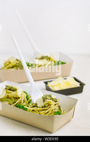 Pasta al pesto decorate con parmigiano in un tradizionale take-away box dal ristorante su sfondo bianco. Ristorante Consegna del cibo Foto Stock