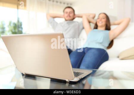 Coppia felice Guarda online il contenuto del laptop relax su un lettino a casa Foto Stock