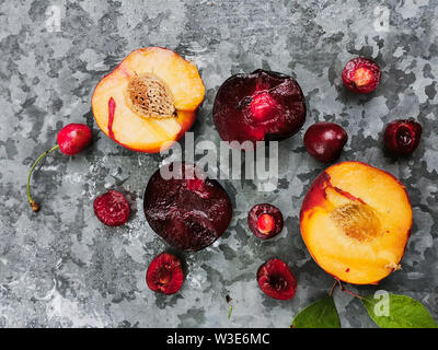 Matura fresca estate di bacche e frutti, pesche, albicocche, ciliegia e prugna in un piatto rotondo sul tavolo Foto Stock