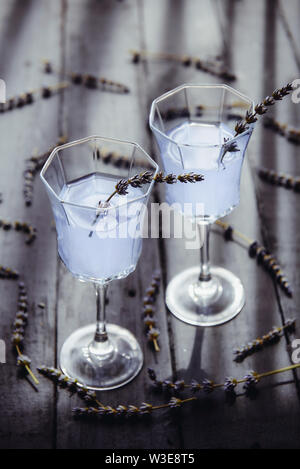 Fresca limonata di lavanda con fiori in splendidi vetri scuri su un tavolo di legno in luce posteriore. Detox acqua. Bevanda estiva. La dieta cocktail. Focu selettiva Foto Stock