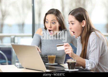 Due sorpreso gli acquirenti online pagando con carta di credito con un computer portatile in un coffee shop Foto Stock