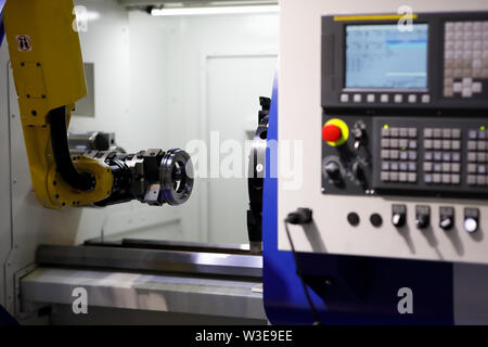 Processo di caricamento automatico dettaglio nel tornio CNC macchina con il braccio di robot. Messa a fuoco selettiva. Foto Stock