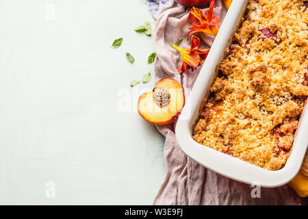 Yummy peach crumble dessert in teglia su sfondo chiaro , vista dall'alto. Spazio di copia per il tuo progetto o ricetta Foto Stock