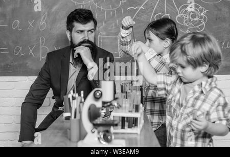 Sviluppo precoce dei bambini. torna a scuola. microscopio strumento ottico a scienza classe. bambini felici insegnante. Imparare mediante microscopio a scuola lezione. Curioso professore a scuola Foto Stock