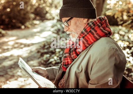 Bel uomo più anziano leggendo un giornale nel parco. Foto Stock
