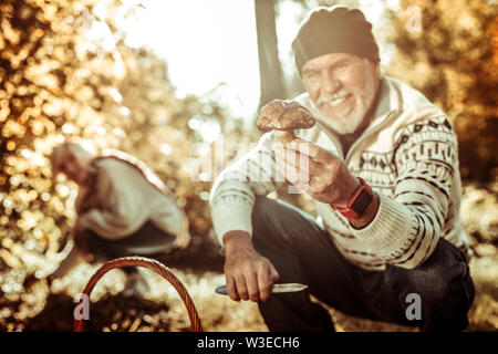 Uomo felice alzando la mano con un grosso fungo. Foto Stock