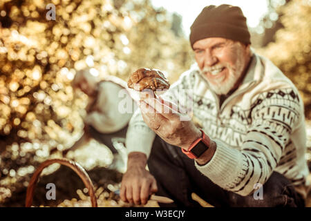 Grosso fungo in una mano di uomo felice. Foto Stock