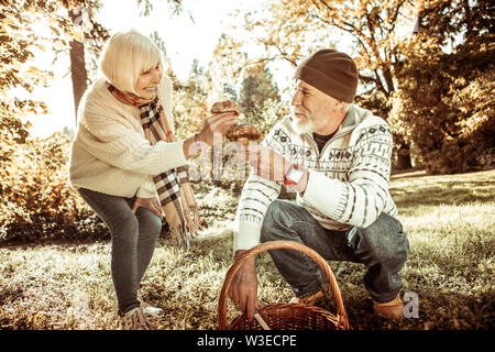 Il marito e la moglie tenendo i funghi nella foresta. Foto Stock