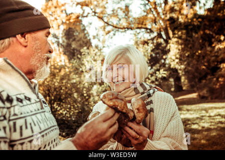 Donna felice tenendo i funghi e guardando il marito. Foto Stock