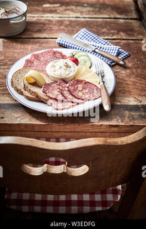 Gustoso pranzo piatto con formaggio e asciugata e indurita con carne di cervo selvatico salsiccia, pane di segale e una cremosa salsa o spalmata su un vecchio tavolo rustico Foto Stock