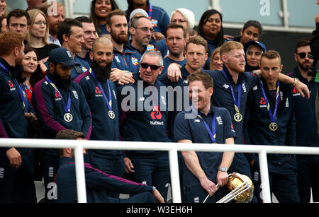 L'Inghilterra del Adil Rashid, Moeen Ali, Trevor Bayliss, Jos Buttler, Ben Stokes, Tom Curran e Eoin Morgan (centro) in posa per una fotografia con compagni di squadra durante la Coppa del mondo le celebrazioni nella Kia ovale, Londra. Foto Stock