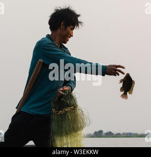 Inle, Myanmar - Marzo 2019: tradizionale birmana gamba pescatore di canottaggio a Lago Inle la cattura del pesce con la mano Foto Stock