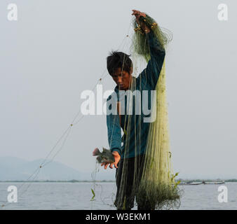 Inle, Myanmar - Marzo 2019: tradizionale birmana gamba pescatore di canottaggio a Lago Inle la cattura del pesce con la mano Foto Stock