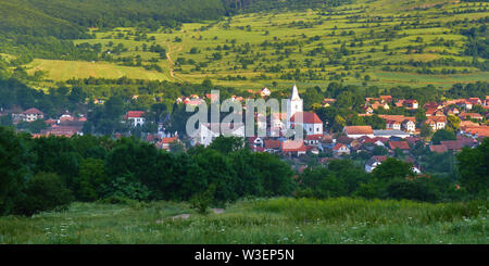 Panorama: Rimetea village (Torocko in ungherese o Eisenmarkt, Eisenburg, Traschen in tedesco) con chiesa bianca e tradizionali case della Transilvania, Foto Stock