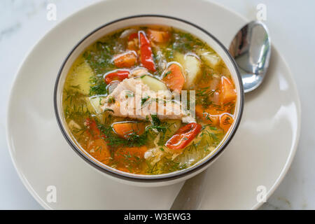 Zuppa di salmone con patate, carote, aneto, pepe in una terrina vicino. Zuppa di pesce e verdure Foto Stock