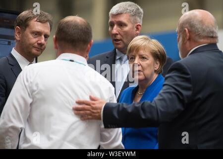 Görlitz, in Sassonia, Germania. Il 15 luglio 2019. Il Cancelliere federale Angela Merkel (CDU) sorge in una sala di produzione presso la Siemens Görlitz impianto a fianco di Michael Kretschmer (CDU, l), il Ministro Presidente del Land di Sassonia e Ronald Schmidt (terza da sinistra), Plant Manager. Un mese e mezzo prima della elezioni di stato della Sassonia, Merkel visite la pianta di Siemens nel libero Stato di Sassonia così come rete di donne riuniti nella capitale dello stato. Foto: Sebastian Kahnert/dpa-Zentralbild dpa/credito: dpa picture alliance/Alamy Live News Foto Stock