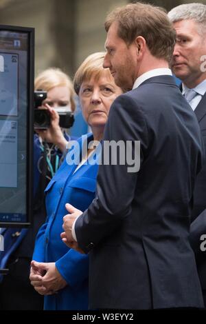 Görlitz, in Sassonia, Germania. Il 15 luglio 2019. Il Cancelliere federale Angela Merkel (CDU) sta in piedi di fronte ad uno schermo in corrispondenza della pianta di Siemens in Görlitz accanto a Michael Kretschmer (CDU), il primo ministro del Land di Sassonia. Un mese e mezzo prima della elezioni di stato della Sassonia, Merkel visite la pianta di Siemens nel libero Stato di Sassonia così come rete di donne riuniti nella capitale dello stato. Foto: Sebastian Kahnert/dpa-Zentralbild dpa/credito: dpa picture alliance/Alamy Live News Foto Stock