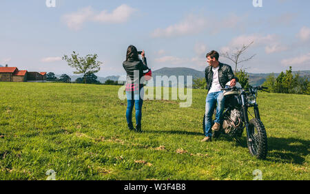 Giovane facendo una foto paesaggistica durante un viaggio in motocicletta Foto Stock