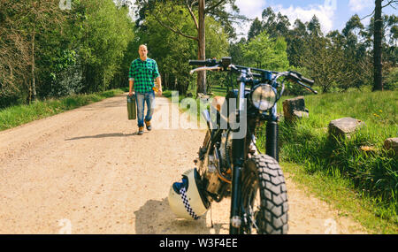 Uomo con benzina può raggiungere a piedi personalizzato moto d'epoca Foto Stock