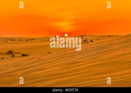 Rosso e arancio i colori del Cielo di tramonto oltre le dune di sabbia al mare interno. Il paesaggio del Deserto vicino a Qatar e Arabia Saudita. Khor Al Udeid, Golfo Persico, medio Foto Stock