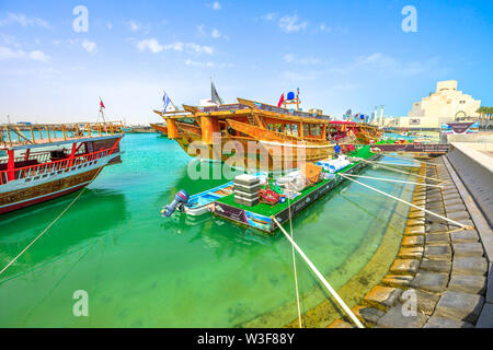 Doha, Qatar - 16 Febbraio 2019: molti dhow di legno ormeggiata al inizio del porto Dhow con il Museo di Arte islamica nella baia di Doha sullo sfondo. Medio Foto Stock