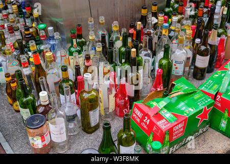 Un sacco di svuotare le bottiglie di vetro in un contenitore di vetro per il riciclaggio. Bordeaux, Gironde. Regione Aquitania. Francia Europa Foto Stock
