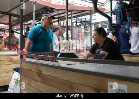 A Belgrado, in Serbia, 13 Luglio 2019: titolare di stallo in chat con un uomo locale a Zemun Mercato verde Foto Stock