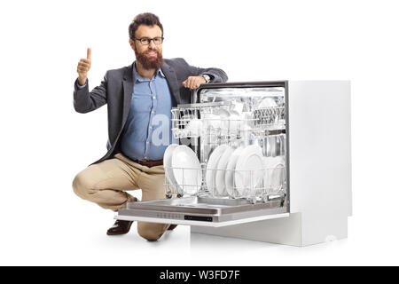 L'uomo inginocchiato accanto ad una lavastoviglie e mostrando pollice in alto isolato su sfondo bianco Foto Stock