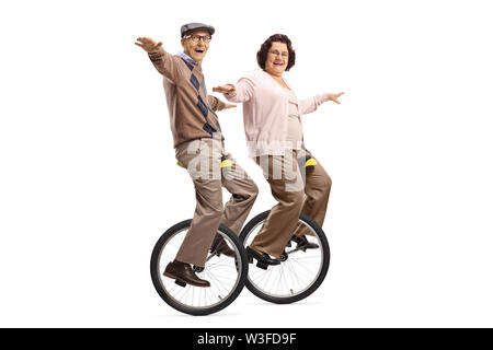 A piena lunghezza shot di un anziano uomo e donna unicycles equitazione e sorridente isolati su sfondo bianco Foto Stock