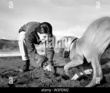 Metà donna adulta giocare felicemente con cane fuori. Foto Stock